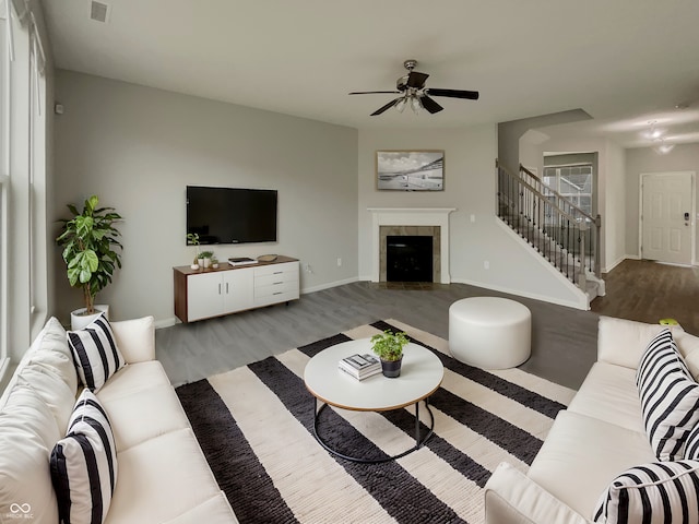 living room with baseboards, visible vents, a tile fireplace, wood finished floors, and stairs