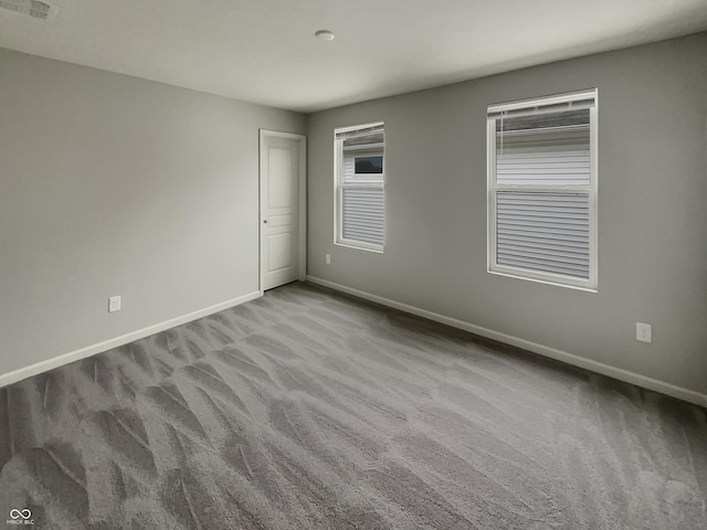 carpeted spare room featuring baseboards