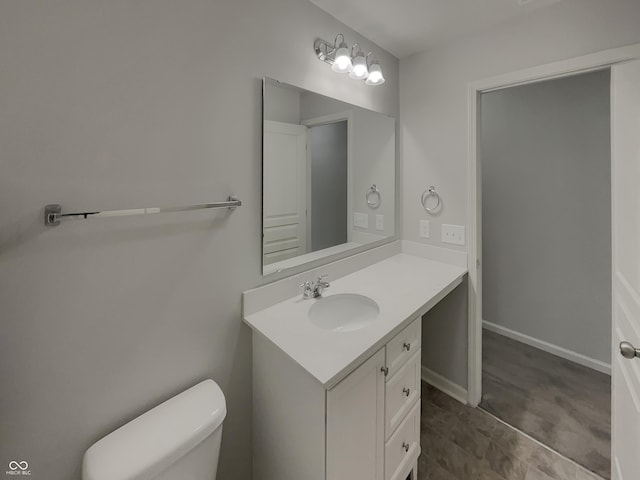 bathroom with toilet, vanity, and baseboards