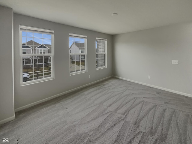 unfurnished room featuring carpet floors, a wealth of natural light, and baseboards