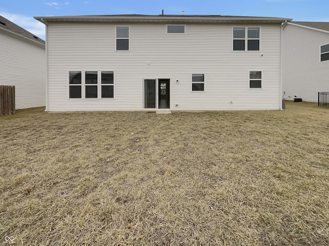 rear view of house featuring fence and a lawn