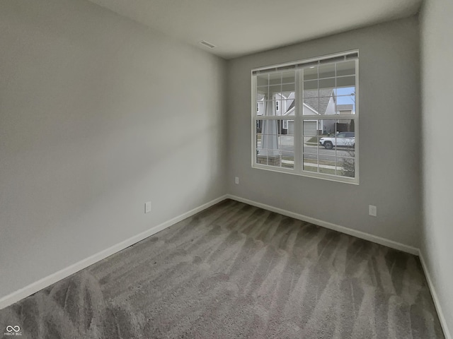 unfurnished room with carpet floors, visible vents, and baseboards