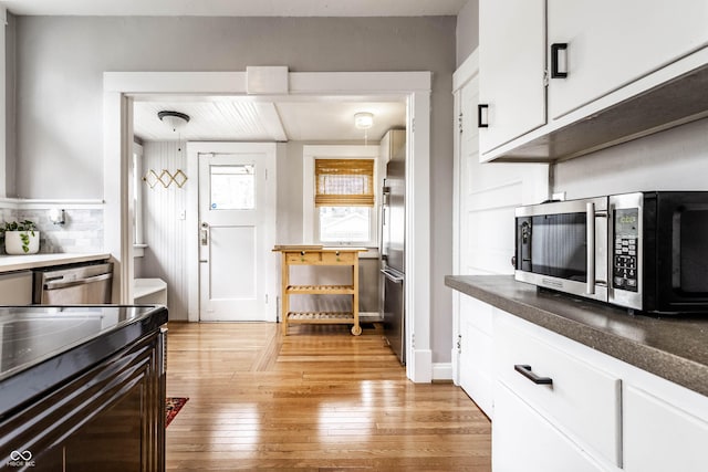 kitchen featuring stainless steel appliances, white cabinets, and light wood-style floors