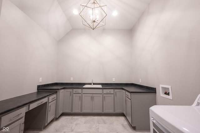 clothes washing area with washer / clothes dryer, a sink, cabinet space, and an inviting chandelier