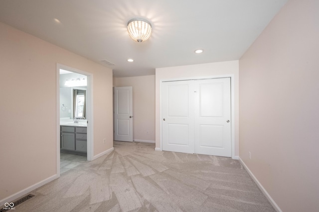 unfurnished bedroom featuring a closet, light colored carpet, visible vents, and baseboards