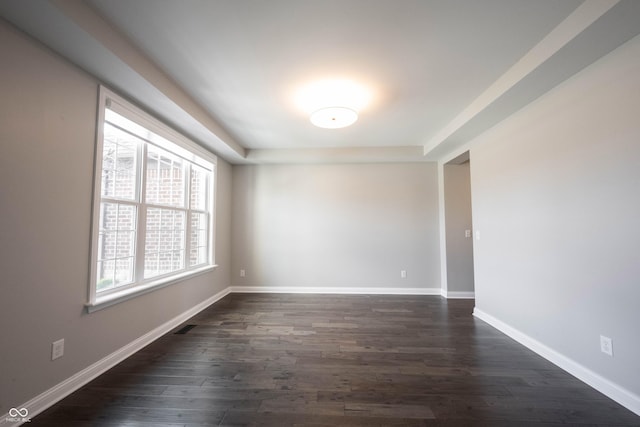 empty room featuring dark wood-style floors, visible vents, and baseboards