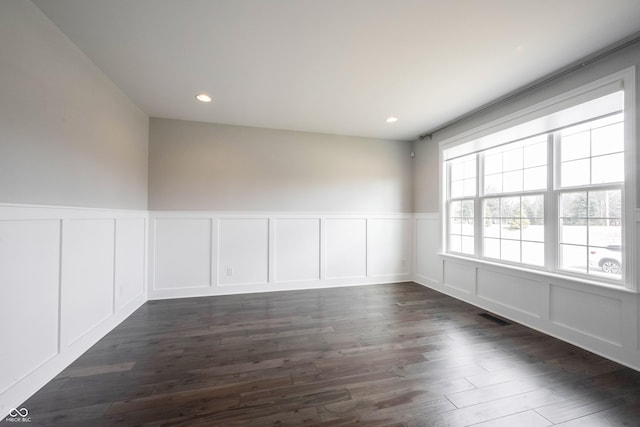 empty room featuring visible vents, a decorative wall, dark wood-type flooring, and recessed lighting