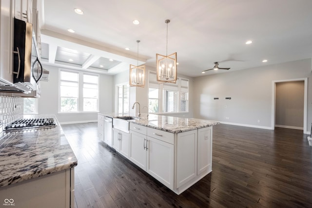 kitchen with stainless steel appliances, dark wood-style flooring, a sink, white cabinetry, and baseboards