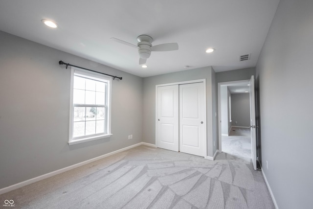 unfurnished bedroom featuring a closet, light colored carpet, visible vents, and baseboards