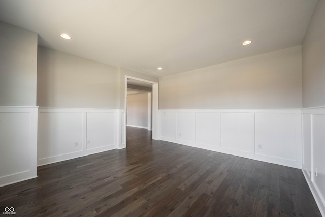 spare room featuring wainscoting, dark wood-style flooring, and recessed lighting