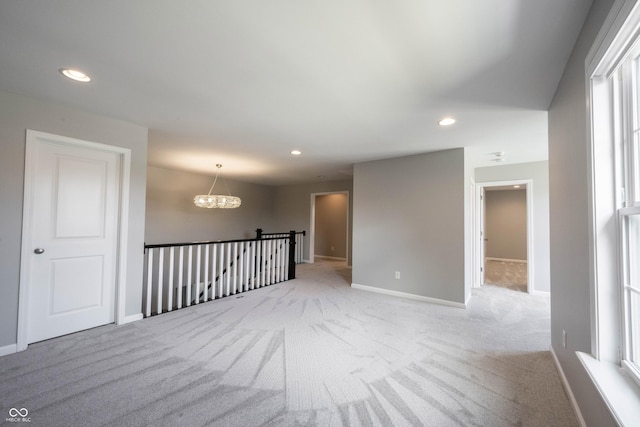 unfurnished room with recessed lighting, carpet, baseboards, and an inviting chandelier