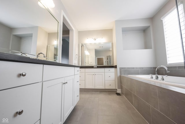 full bath featuring a garden tub, vanity, and tile patterned floors