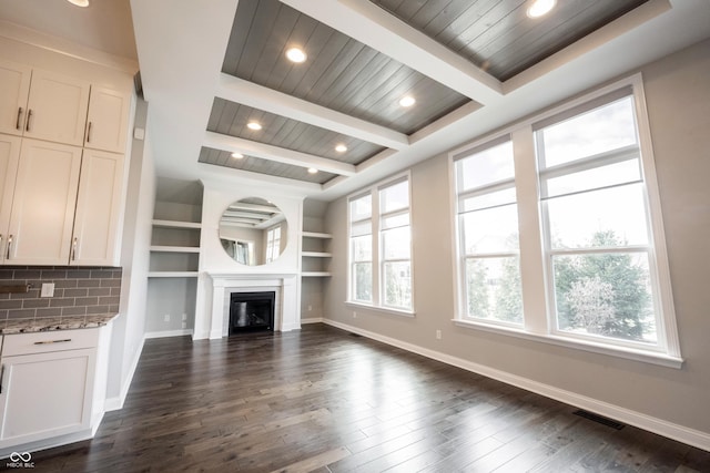 unfurnished living room featuring dark wood-style floors, beamed ceiling, a fireplace, and baseboards