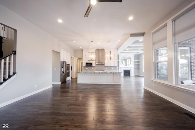 unfurnished living room with dark wood-style floors, a fireplace, baseboards, and stairs