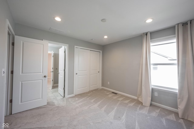 unfurnished bedroom with recessed lighting, a closet, light colored carpet, and baseboards