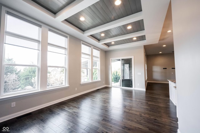 empty room featuring visible vents, baseboards, dark wood-type flooring, and beamed ceiling