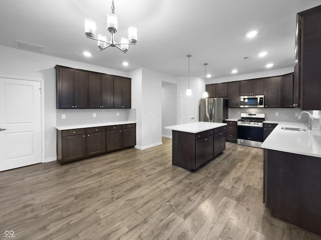 kitchen featuring visible vents, light wood-style flooring, appliances with stainless steel finishes, dark brown cabinets, and a sink