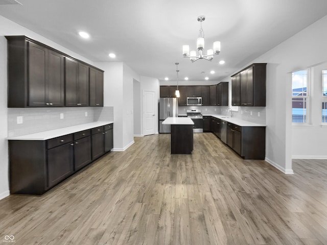 kitchen featuring a sink, light wood-style floors, light countertops, appliances with stainless steel finishes, and backsplash