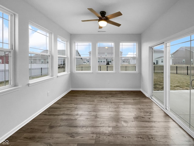 unfurnished sunroom featuring a ceiling fan and plenty of natural light