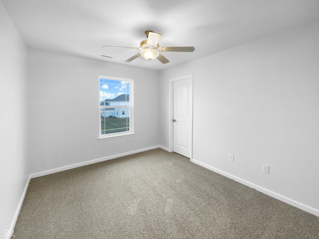 carpeted spare room featuring a ceiling fan, visible vents, and baseboards