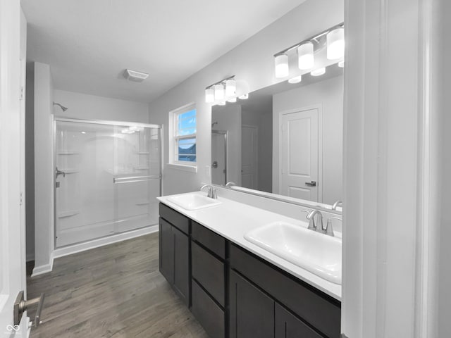 full bathroom featuring visible vents, a sink, a shower stall, and wood finished floors