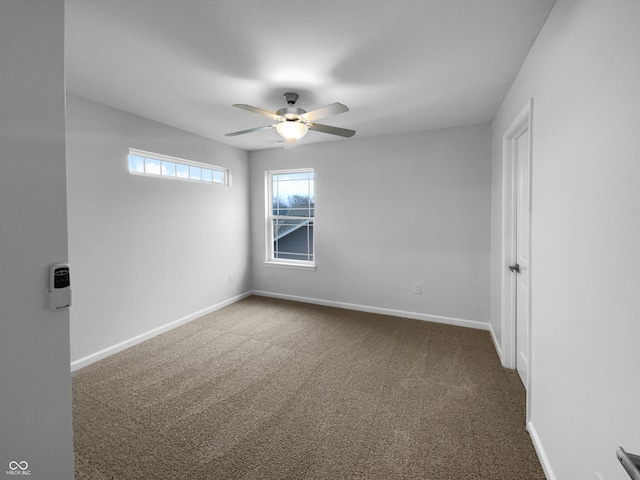 carpeted spare room featuring ceiling fan and baseboards