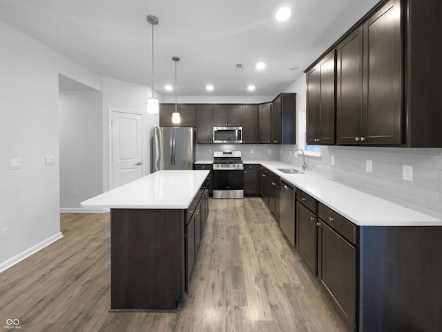 kitchen featuring light wood-type flooring, decorative backsplash, stainless steel appliances, and a sink