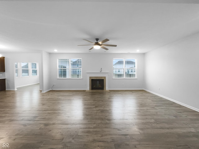 unfurnished living room featuring a fireplace with flush hearth, dark wood finished floors, and a wealth of natural light