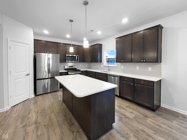 kitchen with light wood finished floors, dark brown cabinets, appliances with stainless steel finishes, and a sink