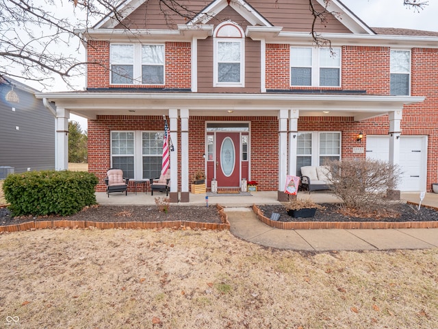 view of front of property with covered porch, brick siding, and a garage