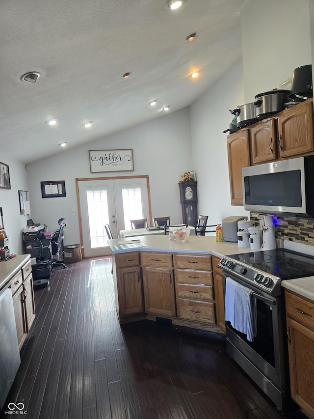 kitchen with lofted ceiling, a peninsula, stainless steel appliances, light countertops, and french doors