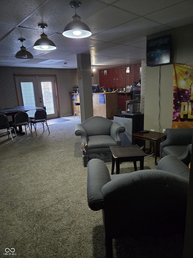 carpeted living room featuring a paneled ceiling, brick wall, and french doors