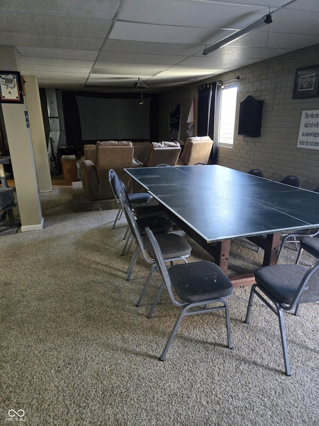 playroom with a paneled ceiling and brick wall