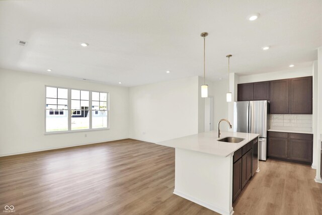 19714 Highclere Ln, Sheridan, IN 46069 - kitchen with decorative backsplash, a sink, light countertops, freestanding refrigerator, and light wood-style flooring