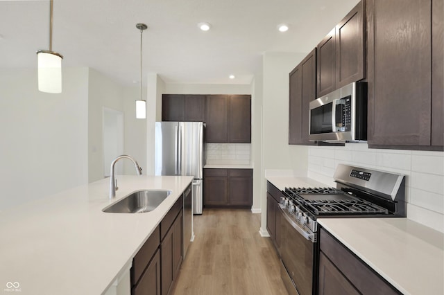 19714 Highclere Ln, Sheridan, IN 46069 - kitchen with dark brown cabinetry, a sink, light wood finished floors, light countertops, and stainless steel appliances