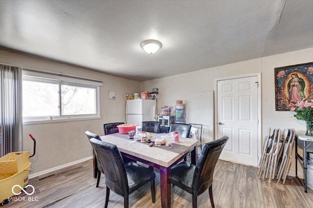 dining space featuring visible vents, baseboards, and wood finished floors