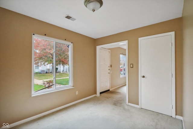 empty room with light colored carpet, visible vents, and baseboards