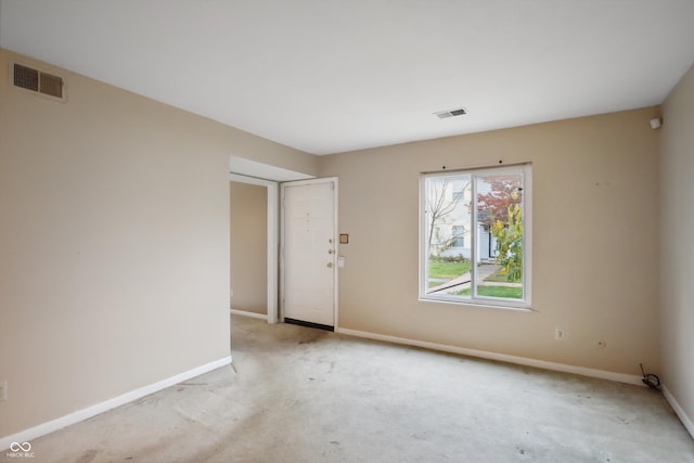 spare room featuring baseboards, visible vents, and light colored carpet