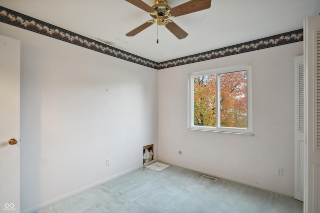 carpeted spare room featuring ceiling fan, visible vents, and baseboards