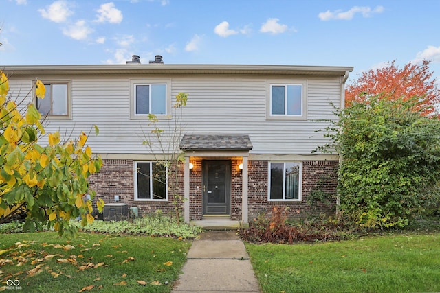 traditional home featuring brick siding, a front lawn, and cooling unit