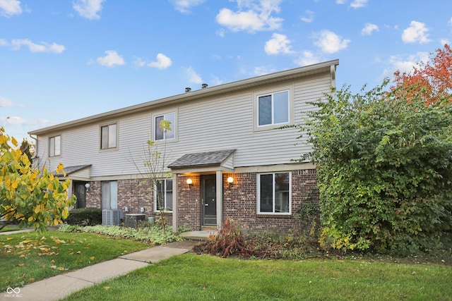 view of front facade featuring a front lawn, central AC, and brick siding