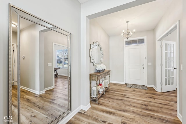 entryway with baseboards, an inviting chandelier, and wood finished floors