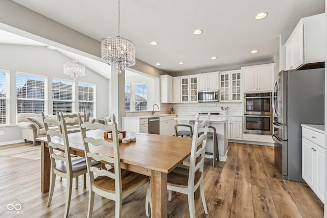 dining room featuring lofted ceiling, an inviting chandelier, light wood-type flooring, and recessed lighting