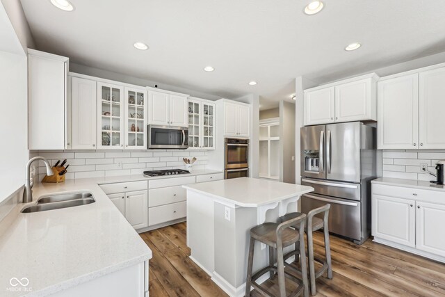 kitchen featuring white cabinets, stainless steel appliances, a sink, and wood finished floors