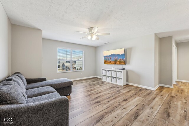 living area featuring wood finished floors, a ceiling fan, and baseboards