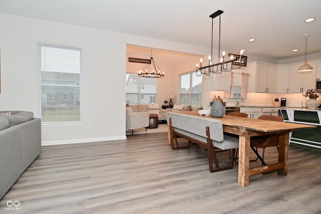 dining space with baseboards, an inviting chandelier, light wood-style flooring, and recessed lighting