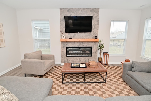 living area with wood finished floors, a high end fireplace, and baseboards