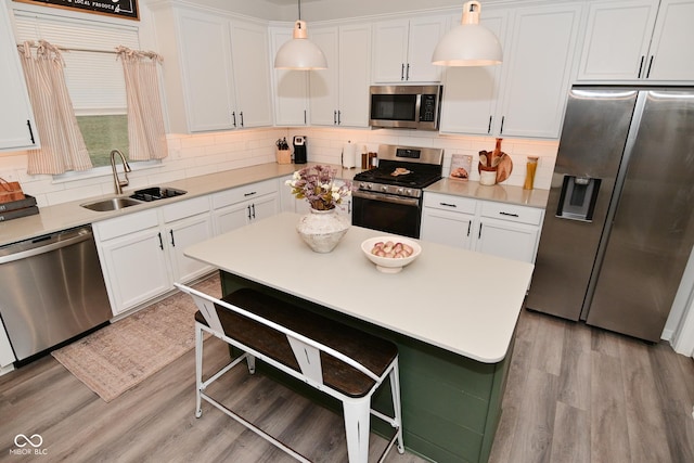 kitchen featuring stainless steel appliances, light wood-style floors, a sink, and a breakfast bar area