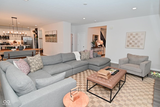 living area with a notable chandelier, recessed lighting, light wood-style floors, baseboards, and stairs