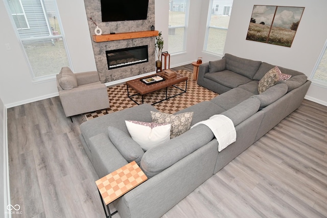 living room with a fireplace, baseboards, and wood finished floors